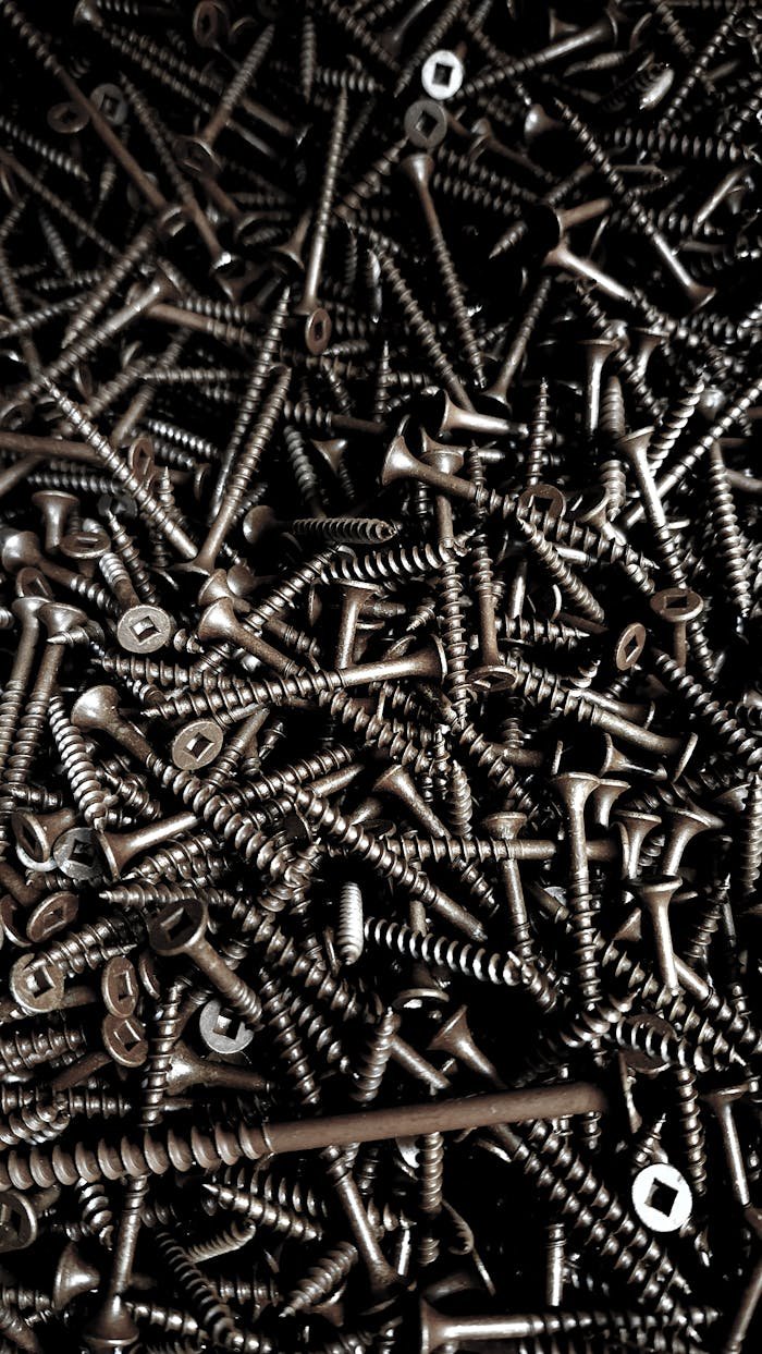 Close-up of numerous metallic screws creating a textured pattern, perfect for industrial projects.